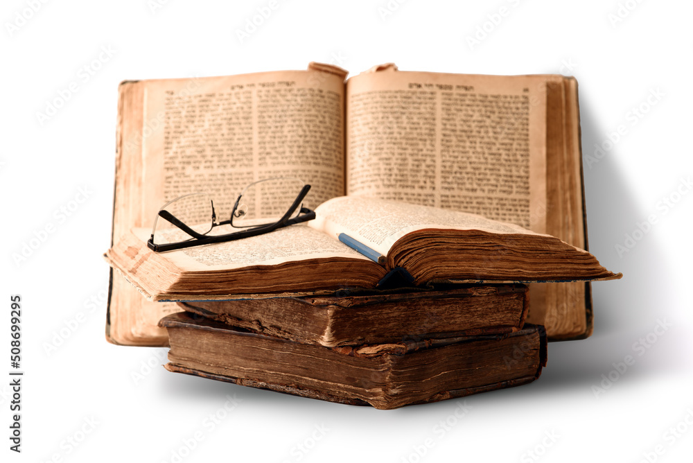 Old worn shabby jewish books in leather binding and open blurred Torah in the background. Closeup. Selective focus.