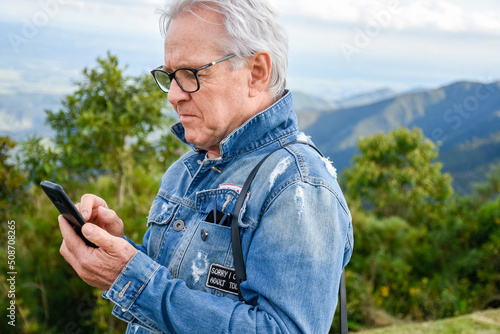 Homem idoso verifica telefone celular durante passeio turístico photo