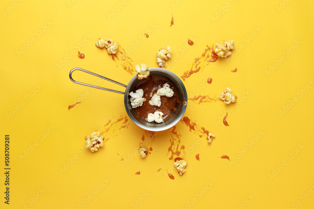 Caramelsweet popcorn in a metal bowl. Caramel explosion. Yellow background. Photography for