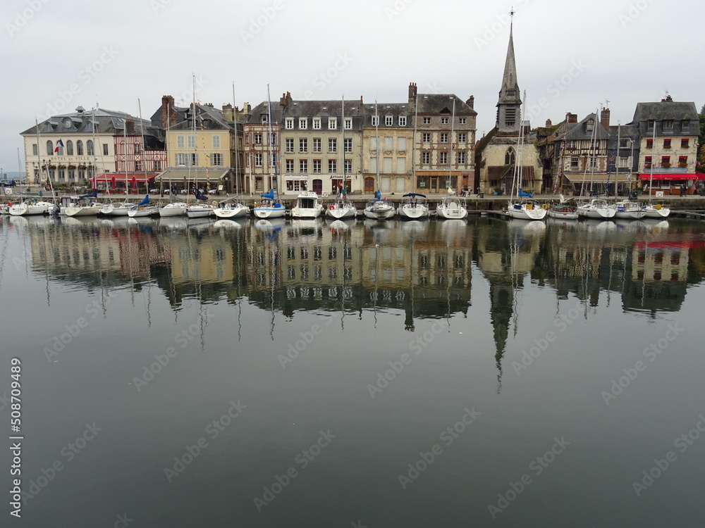 mirror reflection of boats and buildings in the harbor of honfleur, normandy, france