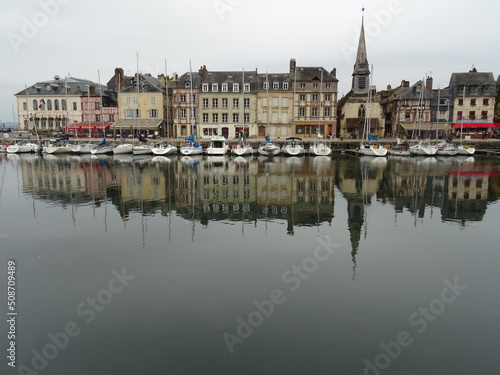 mirror reflection of boats and buildings in the harbor of honfleur, normandy, france