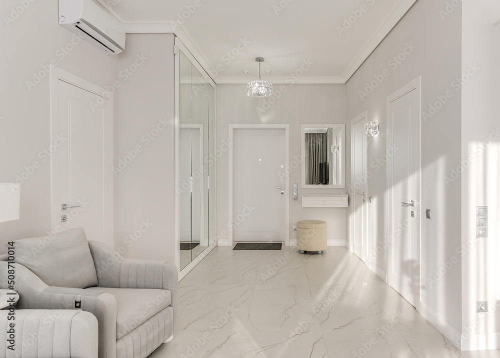 Bright entrance hall in a modern monotonous interior with a large mirrored wardrobe and sun rays Bright entrance hall in a modern monotonous interior with a large mirrored wardrobe and sun rays
