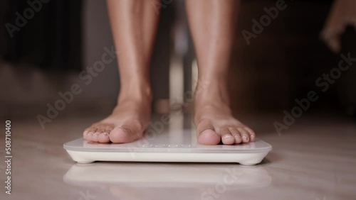 Woman on scales measure weight. girl legs step bathroom scale. Fitness diet woman feet standing weighing. Female dieting checking BMI weight loss. Barefoot measuring body fat overweight. Cinematic 4K photo