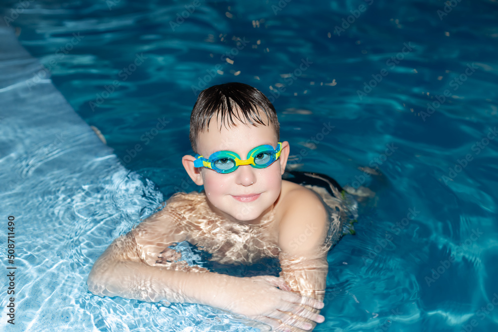 Naklejka premium A smiling boy swims in the pool. Sports and recreation. Leisure activities and lifestyle