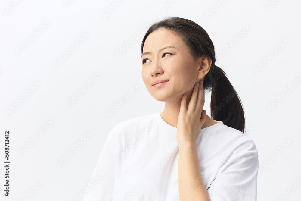 Portrait of suffering sad tanned beautiful young Asian woman touch neck sore throat at home interior living room. Injuries Poor health Illness Cough Tickling concept. Cool offer Banner Portrait of suffering sad tanned beautiful young Asian woman touch neck sore throat at home interior living room. Injuries Poor health Illness Cough Tickling concept. Cool offer Banner