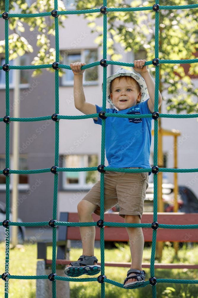 Obraz premium Boy In Adventure Park having fun in high wire park. Male toddler on climbing net.