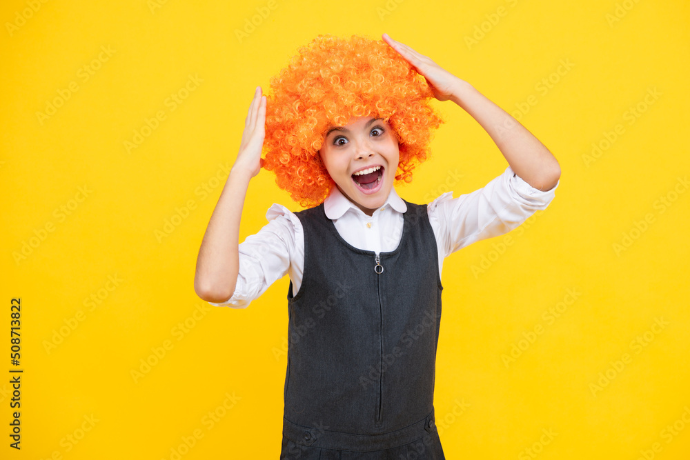 Funny kid in curly redhead wig. Time to have fun. Teen girl with orange hair, being a clown. Surprised face, surprise emotions of teenager girl. Funny kid in curly redhead wig. Time to have fun. Teen girl with orange hair, being a clown. Surprised face, surprise emotions of teenager girl.