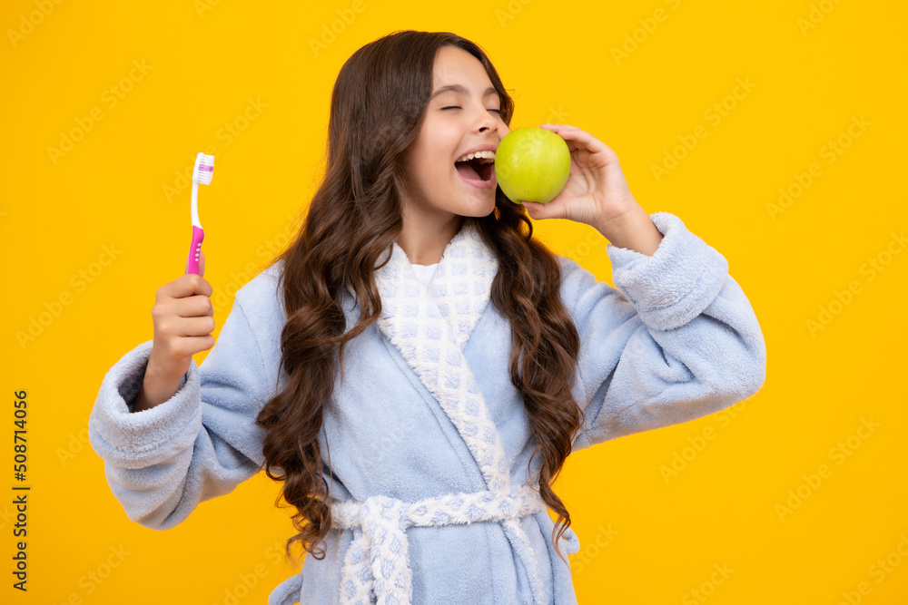 Apple vitamins for healthy teeth. Portrait of caucasian teen girl holds a toothbrush brushing her teeth, morning routine, dental hygiene, isolated on yellow background. Apple vitamins for healthy teeth. Portrait of caucasian teen girl holds a toothbrush brushing her teeth, morning routine, dental hygiene, isolated on yellow background.