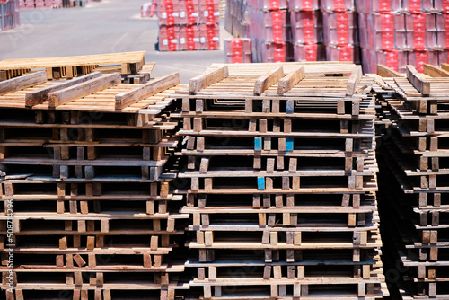 Wooden pallets stacked on a forecourt outside a factory.