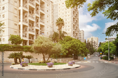 Israeli cityscape with circular motion and decorational flowerbed with flowers in wooden tubs