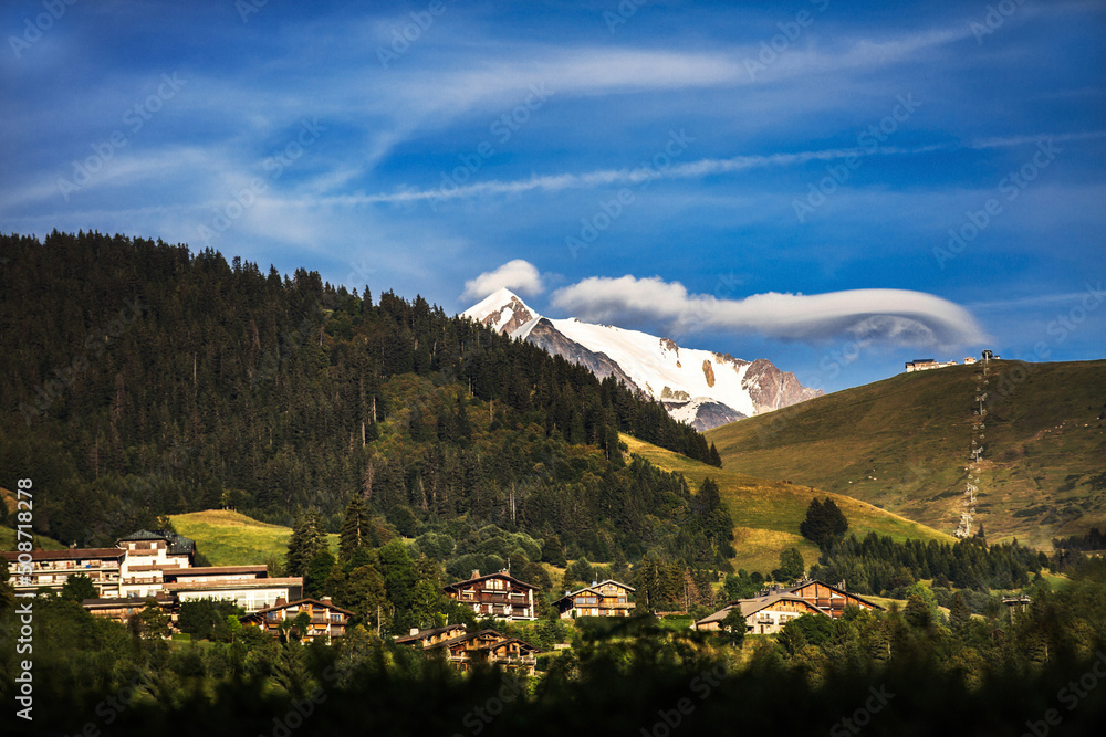 Obraz premium The village is in the mountains. Snow-capped mountains, clouds and forest