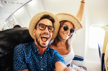 Happy tourist taking selfie inside airplane - Cheerful couple on summer vacation - Passengers boarding on plane - Holidays and transportation concept