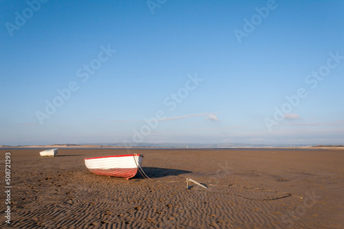 boats on a beach during a sunny day at low tide