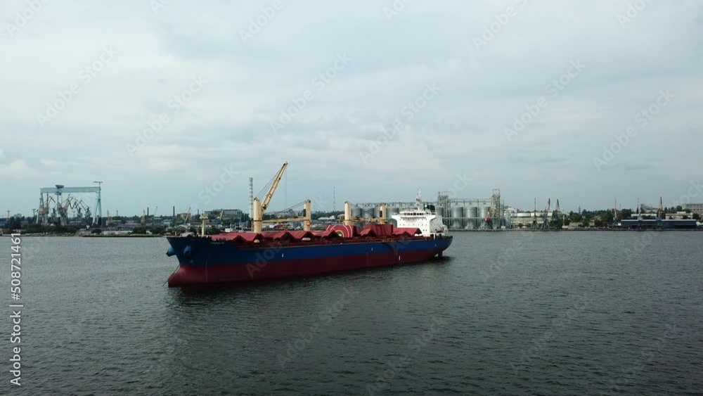 Aerial view of red cargo grain ship floats on the calm sea. Concept of delivering large goods in a cheap way. Aerial view of red cargo grain ship floats on the calm sea. Concept of delivering large goods in a cheap way.