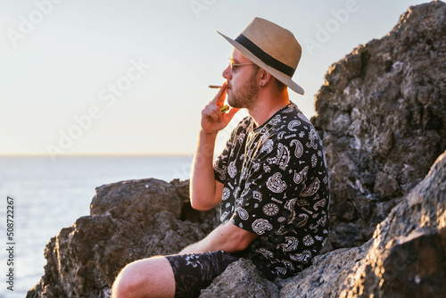 young man smoking a joint in front of the sea