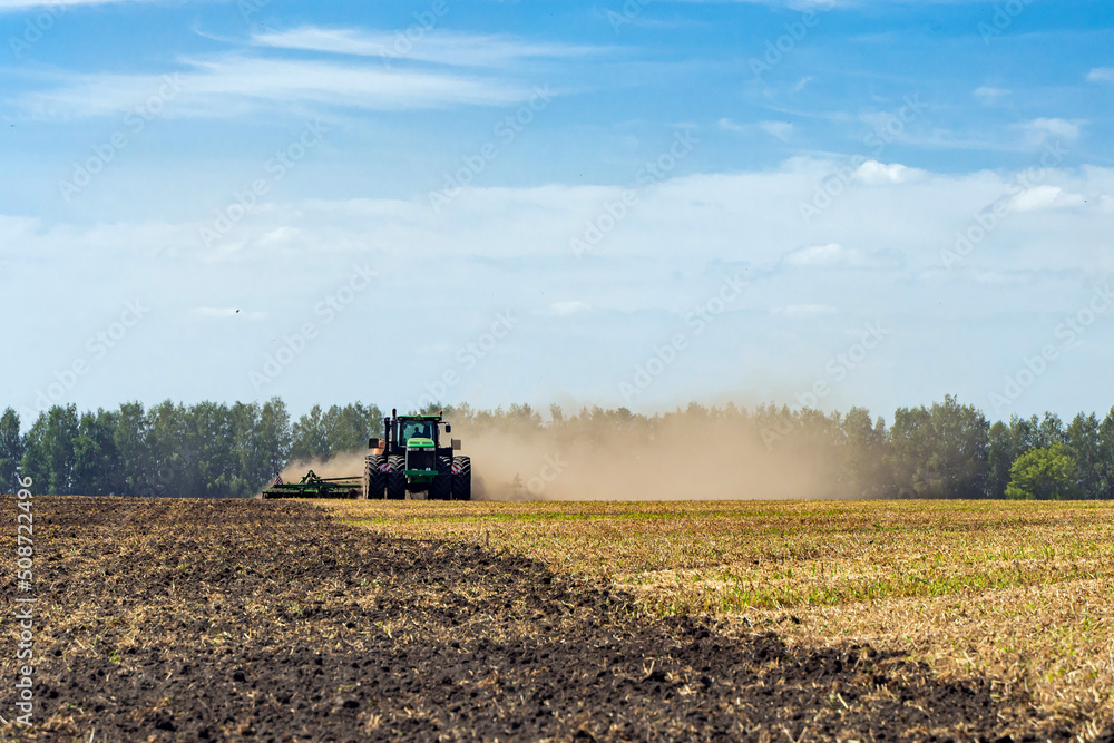 Fototapeta premium The tractor plows the land. Agriculture image.