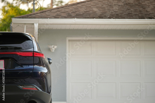Fotografia, Obraz Car parked in front of wide garage double door on concrete driveway of new moder