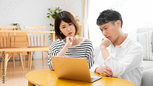 部屋でパソコンで調べ物をする男性と女性 © aijiro