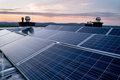 Solar panels located on the roof of the block. Green energy in modern city.  Sunset in the background