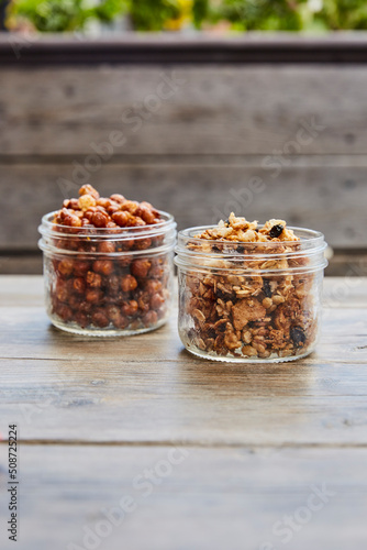 Rosted chickpeas and gronola in jars on a wooden picnic table