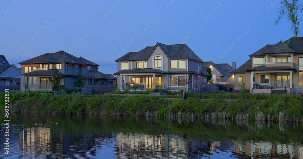 Establishing shot of two story stucco luxury house with garage door, big tree and nice landscape at night in Vancouver, Canada, North America. Night time on May 2022. ProRes 422 HQ. Establishing shot of two story stucco luxury house with garage door, big tree and nice landscape at night in Vancouver, Canada, North America. Night time on May 2022. ProRes 422 HQ.
