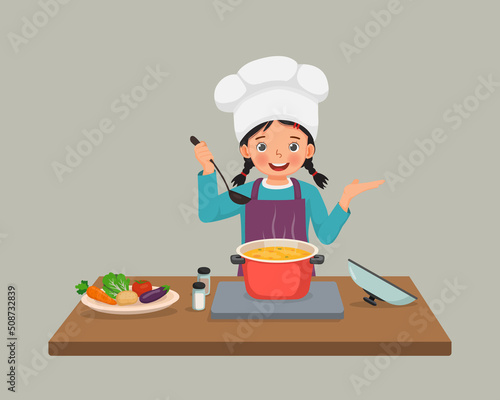 cute little girl chef cooking delicious vegetable soup with hand showing for copy space