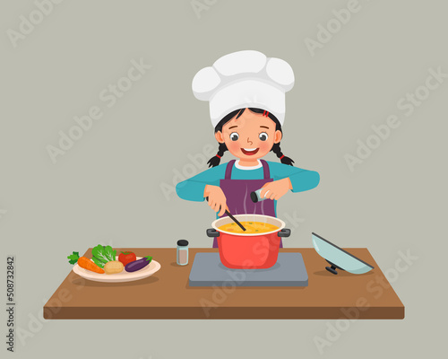 cute little girl chef cooking delicious vegetable soup with pan adding spices in the kitchen