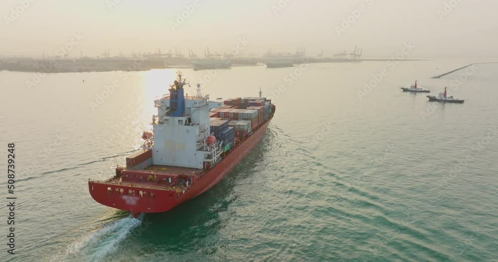 Aerial top view of cargo vessel ship carrying full of container sailing into the yard port at sunset. Concept freight shipping ship sea transport logistics import export. Aerial top view of cargo vessel ship carrying full of container sailing into the yard port at sunset. Concept freight shipping ship sea transport logistics import export.