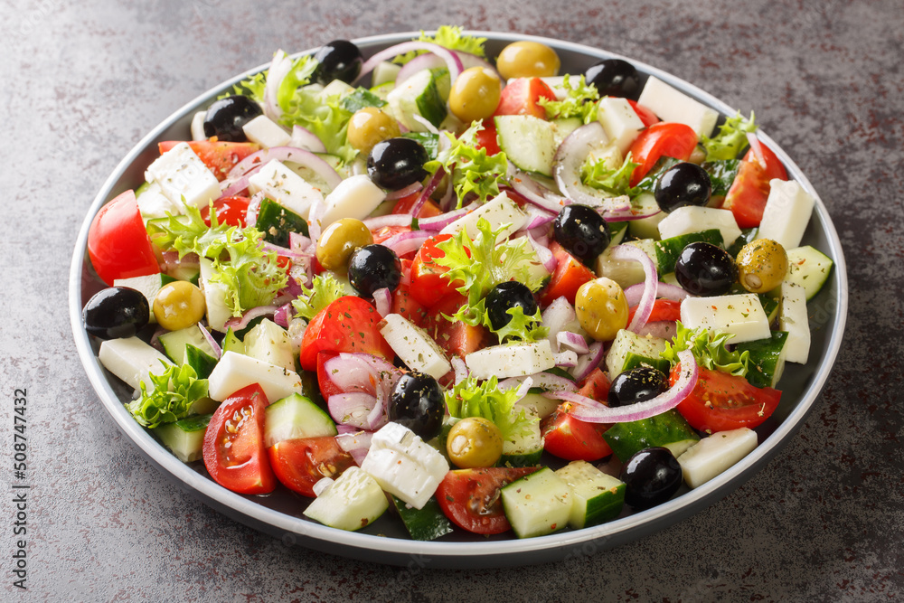 Healthy greek salad of fresh vegetables with tomatoes, lettuce, cucumbers, olives, feta cheese in plate on gray stone background. Healthy food, vegetarian dieting, close up Healthy greek salad of fresh vegetables with tomatoes, lettuce, cucumbers, olives, feta cheese in plate on gray stone background. Healthy food, vegetarian dieting, close up