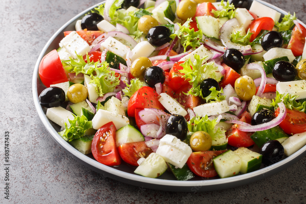 Classic Greek salad from tomatoes, cucumbers, onion with olives, oregano and feta cheese close-up in a plate on the table. Horizontal Classic Greek salad from tomatoes, cucumbers, onion with olives, oregano and feta cheese close-up in a plate on the table. Horizontal