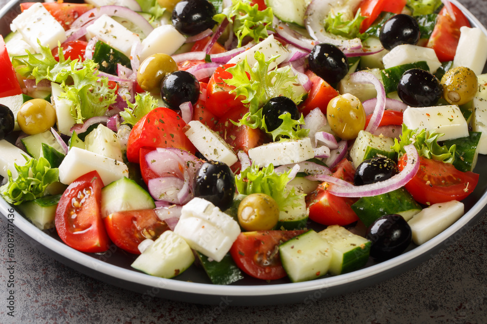 Greek salad with fresh vegetables, feta cheese and black olives close-up in a plate on the table. Horizontal Greek salad with fresh vegetables, feta cheese and black olives close-up in a plate on the table. Horizontal