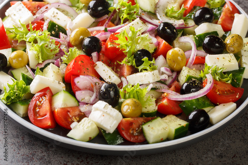 Greek salad with fresh vegetables, feta cheese and black olives close-up in a plate on the table. Horizontal