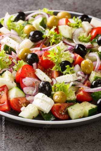 Traditional Greek salad of tomatoes, cucumbers, onions, olives and cheese seasoned with olive oil close-up in a plate on the table. vertical