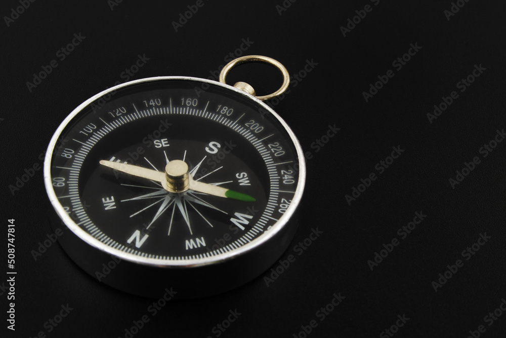 Round compass on black background close-up. Travel, find destination and navigation concept. Round compass on black background close-up. Travel, find destination and navigation concept.