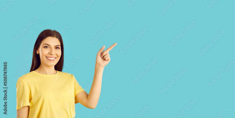 Wide banner of smiling young Caucasian woman isolated on blue studio background point at empty copy space. Happy girl recommend good sale deal or promotion offer. Advertising. Wide banner of smiling young Caucasian woman isolated on blue studio background point at empty copy space. Happy girl recommend good sale deal or promotion offer. Advertising.