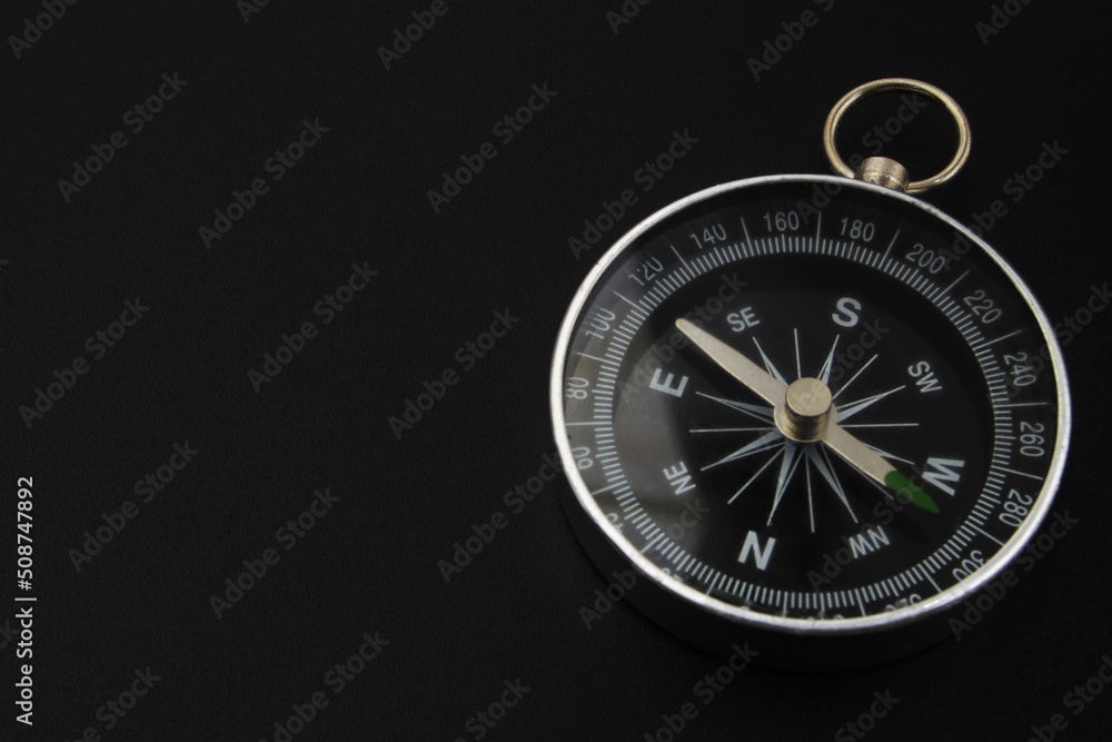 Round compass on black background close-up. Travel, find destination and navigation concept. Round compass on black background close-up. Travel, find destination and navigation concept.