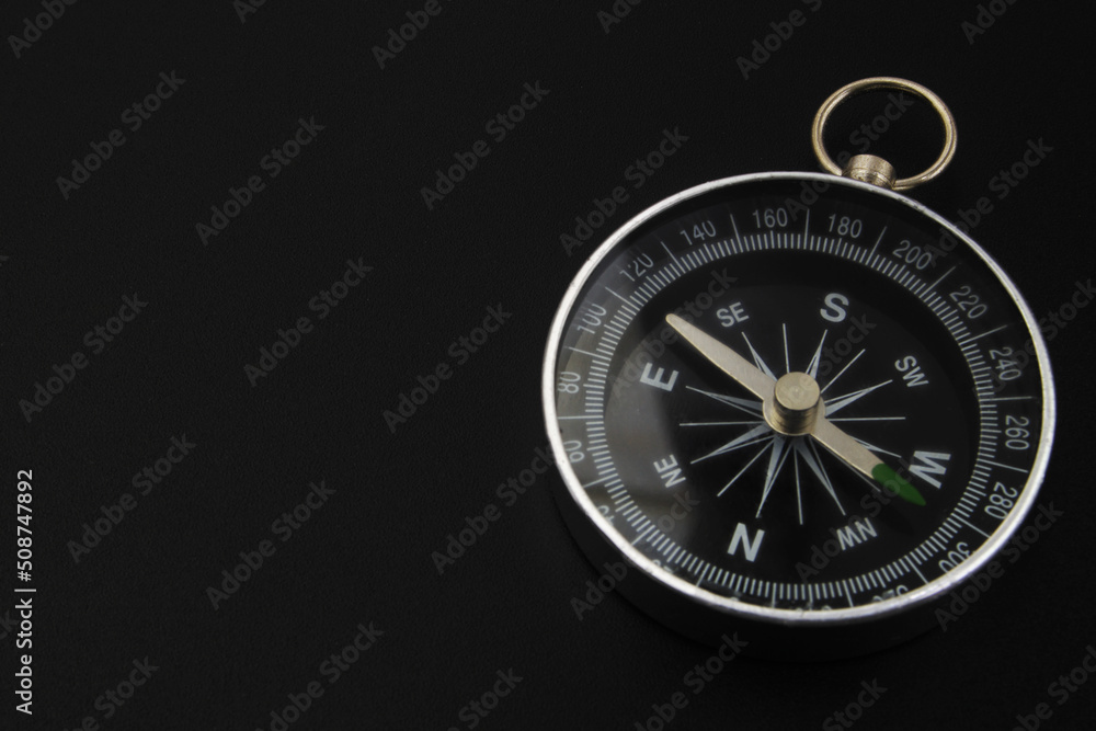 Round compass on black background close-up. Travel, find destination and navigation concept.