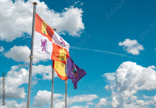 Banderas de Castilla y León, España y provincia de Palencia ondeando al viento con cielo y nubes de fondo photo