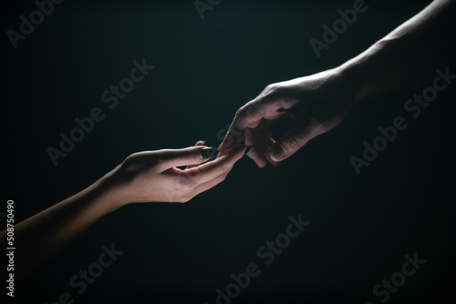 Two hands reaching toward. Tenderness, tendet touch hands in black background. Romantic touch with fingers, love. Hand creation of adam.