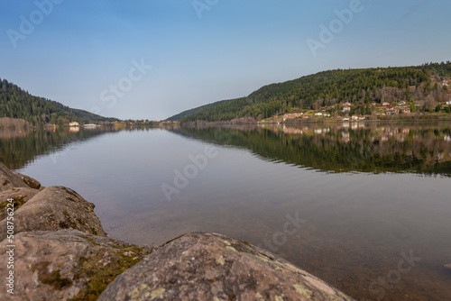 Lac de Gérardmer dans les Vosges un matin de printemps. Surface de l'eau calme comme un miroir sous un ciel bleu.