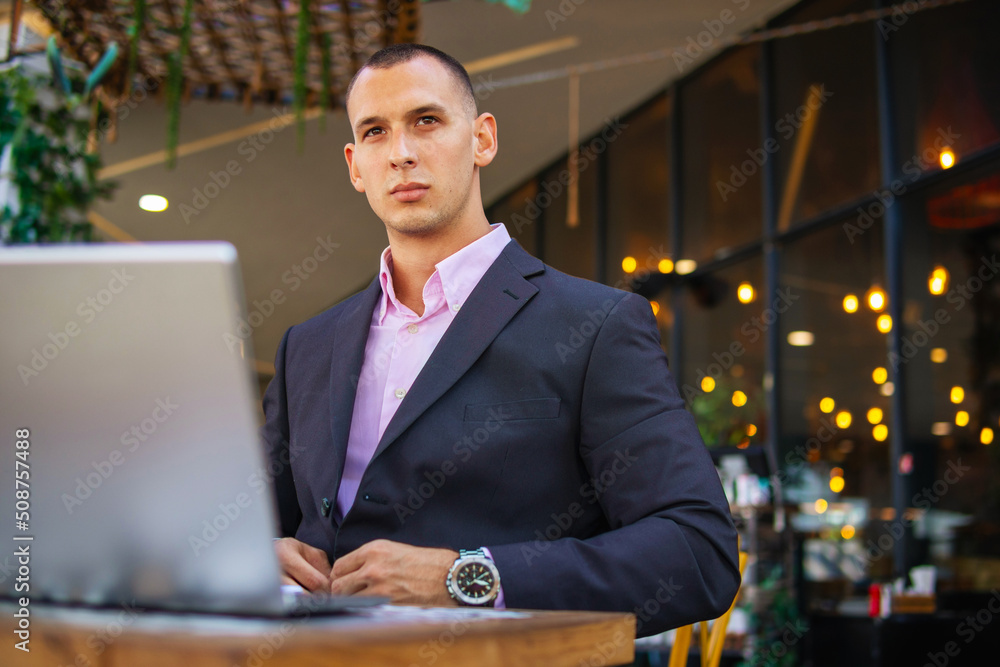 Young handsome businessman working on his laptop while sitting in a cafe Young handsome businessman working on his laptop while sitting in a cafe