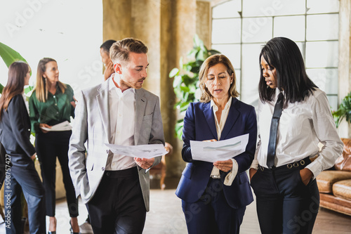Adult businesswoman talking about financial report with her staff, mixed age range group of business and finance people, open space for workteam