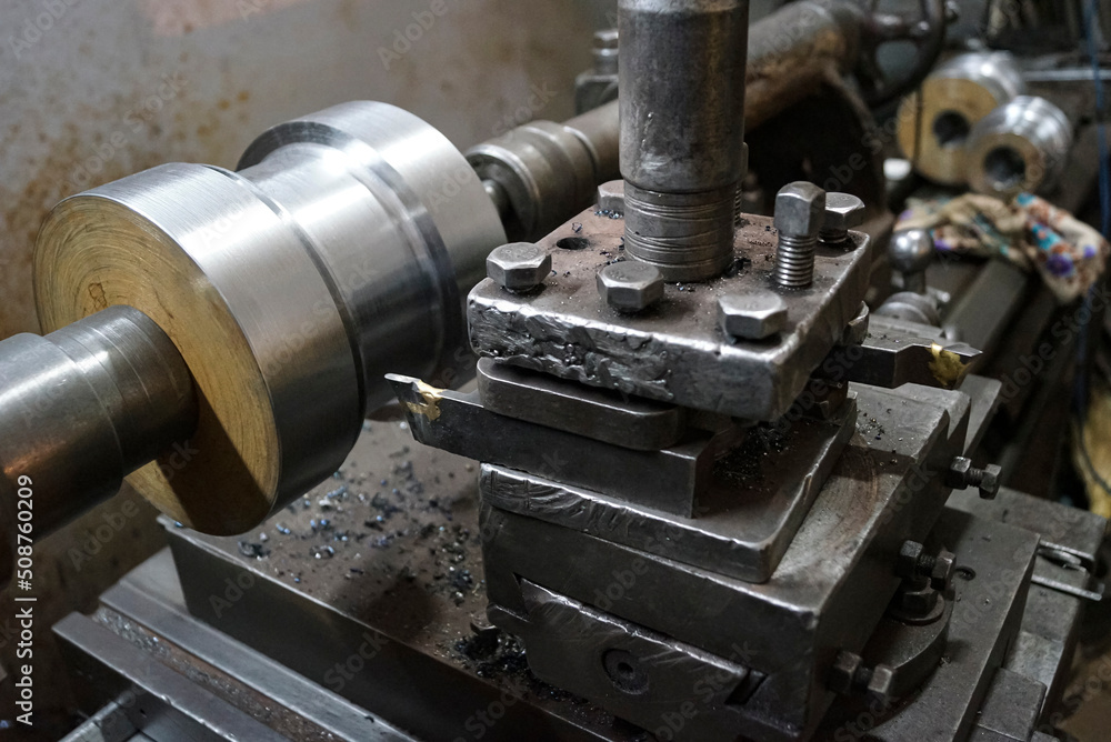 Closeup of a metal shaft parts cutting by metal cutter of old Lathe Machinery. Vintage Industrial Machinery in a old factory. Selective focus. Closeup of a metal shaft parts cutting by metal cutter of old Lathe Machinery. Vintage Industrial Machinery in a old factory. Selective focus.