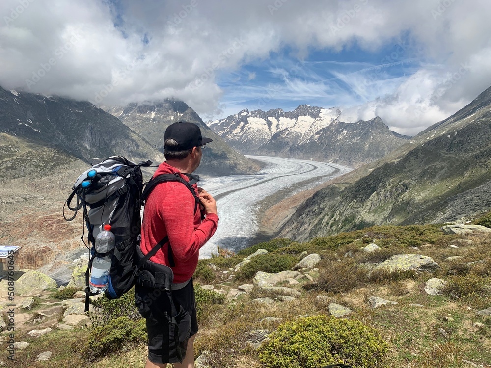 Wanderer, Bergführer schaut auf Aletschgletscher und die Walliser Berge Aletschhorn, Jungfrau Joch, Bettmerhorn auf der Riederalp im Wallis. - grösste und längste Gletscher der Alpen / Schweiz Wanderer, Bergführer schaut auf Aletschgletscher und die Walliser Berge Aletschhorn, Jungfrau Joch, Bettmerhorn auf der Riederalp im Wallis. - grösste und längste Gletscher der Alpen / Schweiz