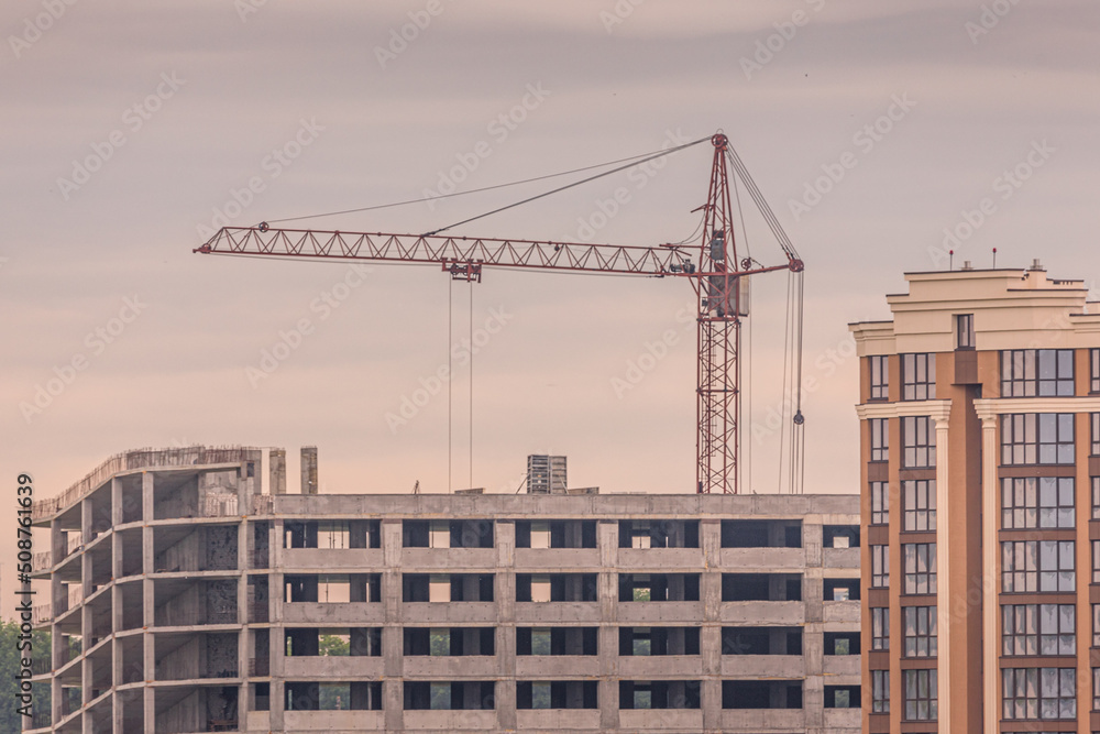 Real estate market. New building. Construction crane. Unfinished residential complex. Reliable developer. Luxury housing in the city. Urban view.