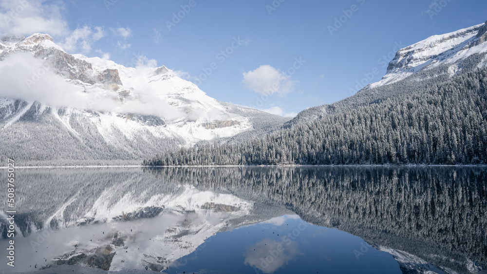 Still alpine lake reflecting its winter surroundings like a mirror, wide, Yoho N. Park, Canada
