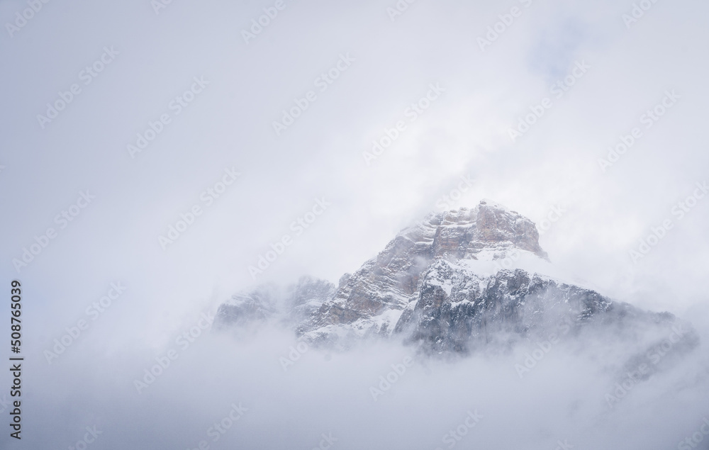 Isolated snowy alpine peak shrouded by clouds and fog, Yoho N. Park, Canada