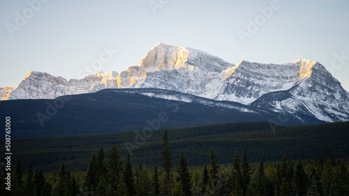 Massive rocky mountain catching the first sun rays on a cold winter morning, wide, Banff NP, Canada
