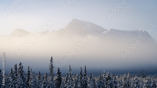 Big mountain emerging from fog during cold winter morning , Banff N. Park, Canada