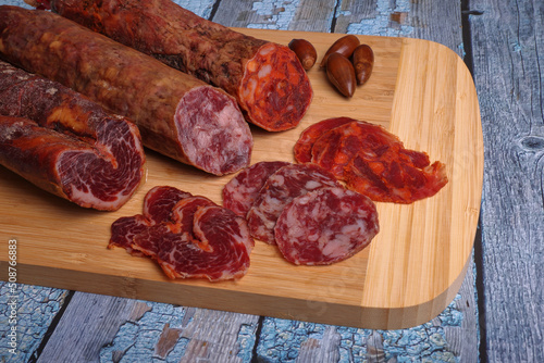 Iberian sausage, Iberian chorizo and Iberian loin on cutting board and blue wooden table.